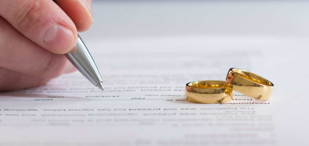 Pen and wedding rings on divorce paperwork